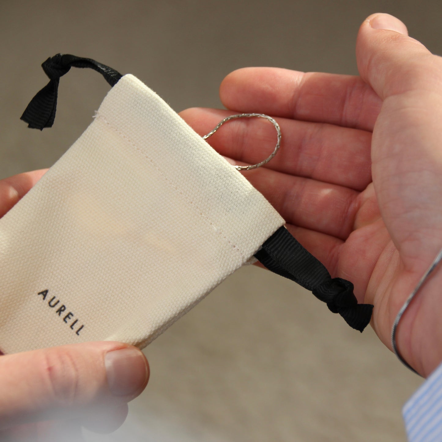 Edelstahl Armband, geflochten mit AURELL Logo in Stoffbeutel mit Herrenhand
